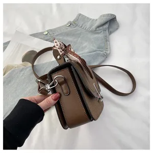 Detailed view of casual brown women's crossbody bag with elegant scarf and shoulder strap.