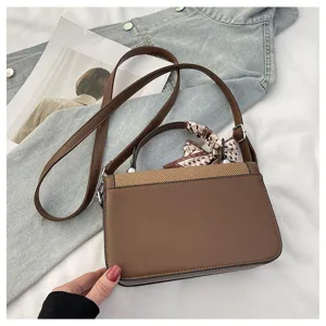 Brown PU leather crossbody shoulder bag detail with elegant small scarf and denim background.