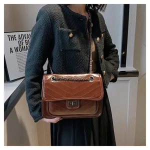 Brown patent leather shoulder bag detail with chevron stitching and metal chain strap.