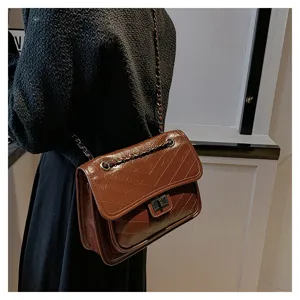 Brown quilted chain shoulder bag detail showing premium leather texture and metal lock design.