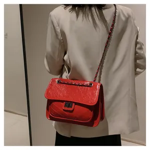 Red quilted chain shoulder bag detail shot, showing textured leather and metallic turn-lock.