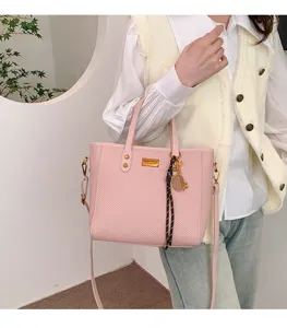 Detailed view of the stylish pink woven tote bag with shoulder strap and chic hanging charm.