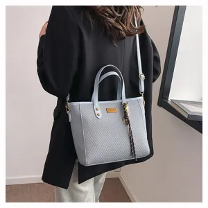 Detail shot of light blue woven tote bag worn on shoulder, stylish commuter accessory.