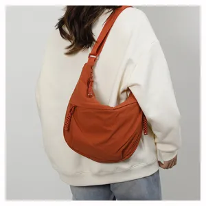 Detail view of the orange casual crossbody dumpling bag showing its back wear style and strap.