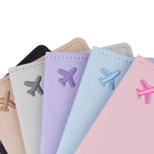 Nahaufnahme Detail der Pastell Leder Reisepasshülle mit süßem gesticktem Flugzeugdesign.