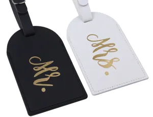 Close-up detail of couple luggage tags in black and white PU leather with gold lettering.