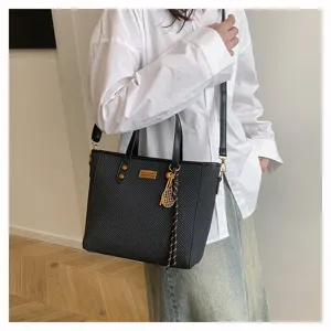 Detail view of a black woven texture tote shoulder bag with dual handles and gold charm.