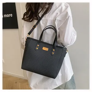 Close-up of a stylish black textured tote bag with top handles and a shoulder strap.