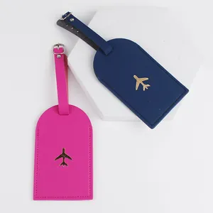 Dettaglio etichetta bagaglio in pelle, porta carte viaggio rosa e blu con aeroplano dorato.