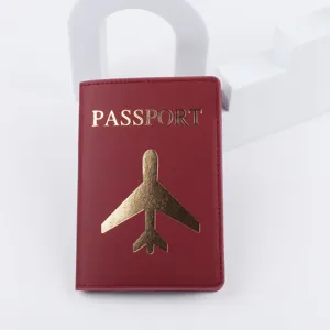 Dettaglio ravvicinato del porta passaporto in pelle PU rossa con aereo e testo dorati.