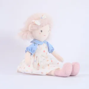 Plush doll detail view featuring pink fluffy hair with bow, blue collared dress and printed skirt.