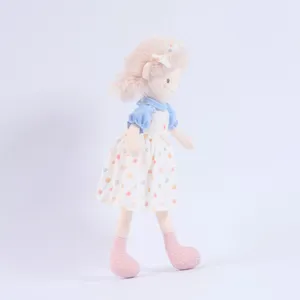 Cute plush girl doll detail view, soft fabric comforting toy with lovely dress and pink hair.
