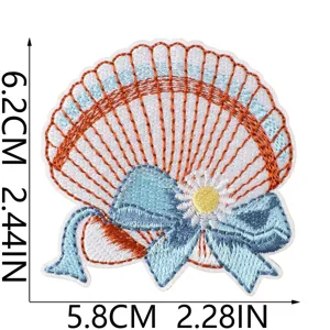 Close-up detail of the shell embroidery patch featuring blue bow and flower design.