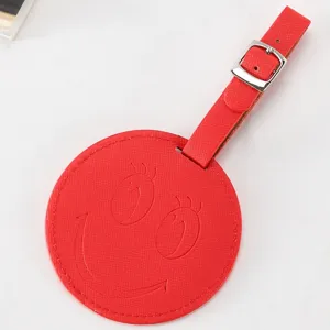 Étiquette de bagage ronde en cuir PU rouge avec design gaufré smiley et sangle à boucle métal.