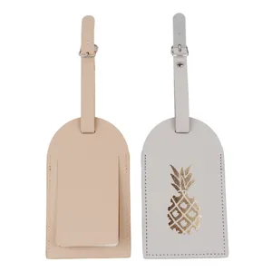 Primo piano di etichette per bagagli in pelle con cinturino regolabile e motivo ananas dorato.