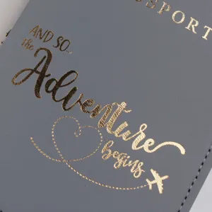 Primo piano di porta passaporto in pelle PU grigia con elegante scritta dorata e aereo.