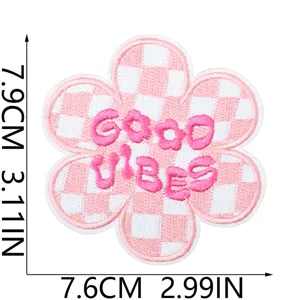 Détail de patch brodé de fleurs à carreaux roses et blancs avec texte Good vibes.