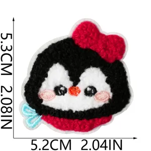 Close-up detail of cute penguin iron-on patch with red bow, soft plush embroidery texture.