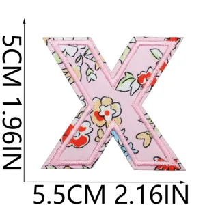 Primo piano dettagliato del patch lettera X ricamata con stampa floreale e bordo rosa.