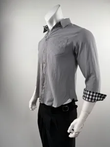 Dettaglio camicia uomo grigia a manica lunga con colletto e polsini a quadri bianchi e neri.