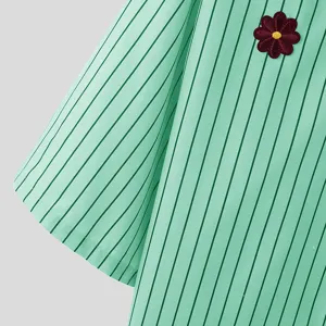 Detailaufnahme eines karierten Kurzarmhemds für Herren in Mintgrün mit gesticktem Blumenaufnäher.