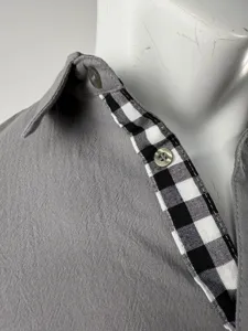 Dettaglio ravvicinato di una camicia grigia da uomo a maniche lunghe con colletto a quadri.