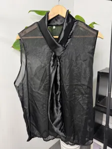 Gedetailleerd overzicht van zwarte mouwloze mesh top met satijnen halsstrik hangend.