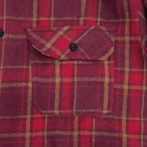 Detailed view of men's vintage plaid flannel shirt chest pocket texture and buttons design.
