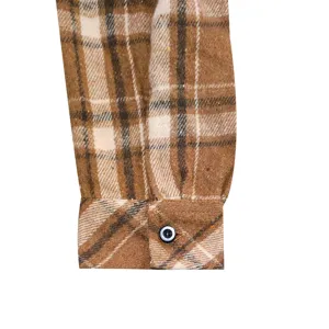 Close-up view of men's brown plaid flannel shirt cuff detail, vintage casual style.