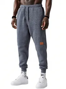 Vista dettagliata dei pantaloni felpati da uomo in grigio scuro con coulisse e polsini.
