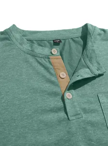 Close-up detail of men's green henley t-shirt collar, button placket, and chest pocket.