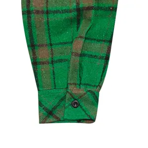 Green plaid flannel shirt sleeve cuff detail with single black button, casual autumn men top.