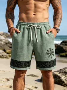 Close-up detail of green linen-blend beach shorts featuring Viking totem print and drawstring.