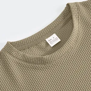 Detailaufnahme des strukturierten khaki Herren T-Shirt-Kragens mit Etikett und Stoff.