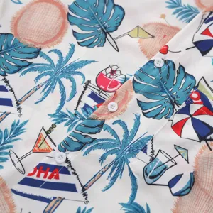 Detailed view of men's tropical Hawaiian print short-sleeve shirt fabric and buttons.