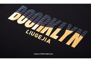 Close-up detail of stylish gradient metallic letter print on black fabric streetwear T-shirt.