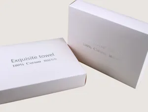 Détail de boîte cadeau blanche montrant un emballage de serviette avec lettrage argenté.