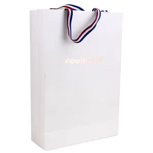 White paper gift bag detail view showing sturdy red white and blue ribbon handles.