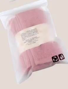 Pink cotton towel detail view showing packaging bag and fabric texture, soft material