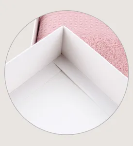 Vue détaillée de la boîte cadeau pour serviette blanche avec beau textile rose.