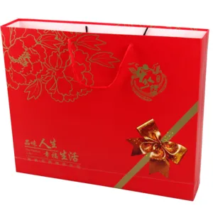 Red paper gift bag with gold peony and ribbon design, perfect for wedding and holiday wrapping.