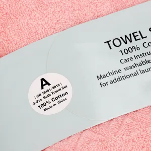 Vue détaillée d'un ensemble de serviettes roses en coton avec étiquette et texture.