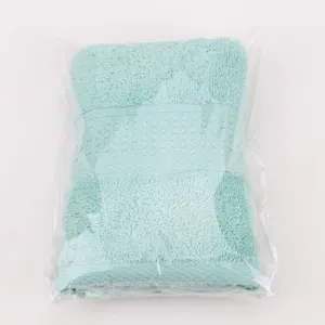 Vue détaillée d'une serviette pliée vert menthe unie avec bande texturée sous sachet.