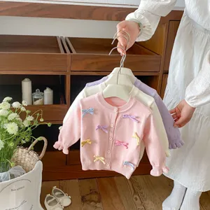 Close-up of toddler knit cardigan with cute colorful bows, soft fabric, detailed view.