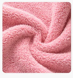 Detailopname van zachte roze katoenen badhanddoek met absorberende lusstructuur voor thuis.