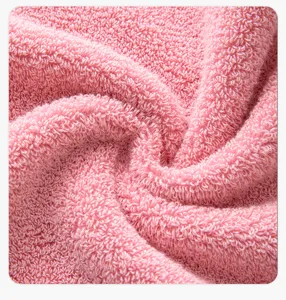 Détail de gros plan de serviette de bain en coton rose montrant sa texture éponge.