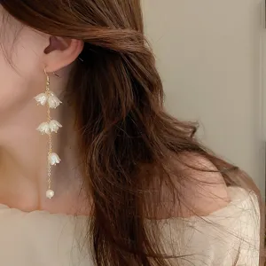 Vue détaillée d'élégantes boucles d'oreilles à pampilles en acrylique blanc sur un modèle