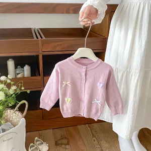 Cute knit cardigan detail showing pink fabric, bow applique, and sweet heart embroidery.