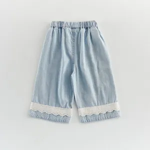 Details of girls light blue denim shorts with sweet white lace trim and elastic waist design.