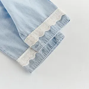 Detailed shot of light blue children denim pants cuff with delicate white lace trim.